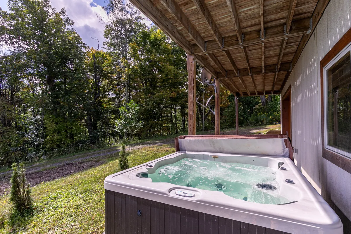 The private outdoor hot tub nestled on the deck, surrounded by trees for privacy and immersed in a peaceful natural setting. The structure highlights both the hot tub and the deck area, reinforcing the sense of retreat and relaxation after a day of exploration.