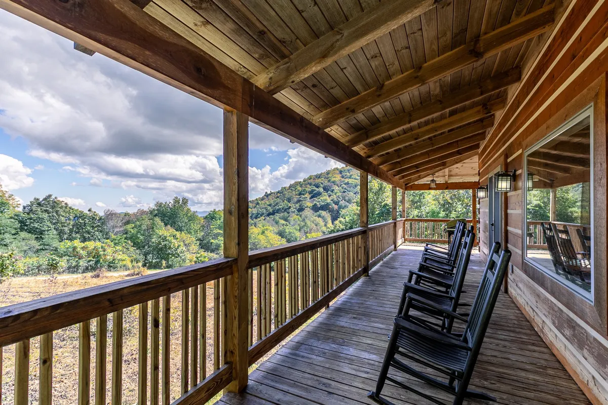 A tranquil scene of the cabin’s exterior deck, featuring classic wooden rocking chairs and a sturdy railing overlooking an expansive mountain view. The setting is open to nature, ideal for soaking in the High Country’s crisp air and scenic beauty.
