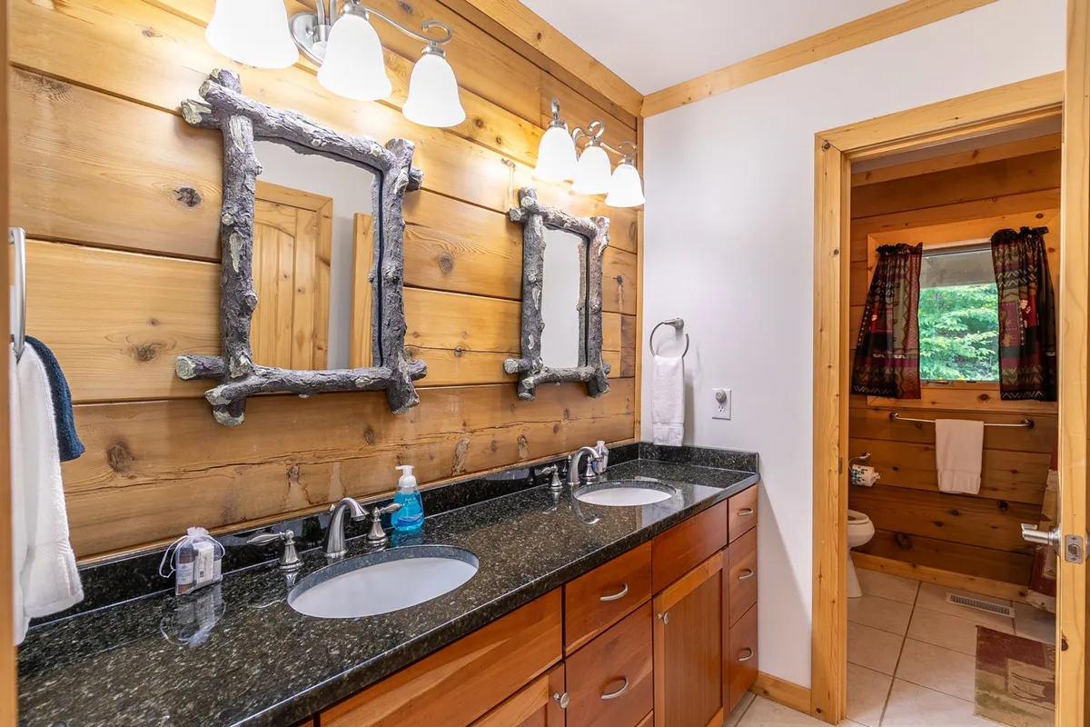 A spa-inspired bathroom featuring a double sink vanity, framed mirrors, and warm wooden wall paneling. The space feels fresh and functional, ideal for busy mornings or relaxing routines after outdoor adventures.